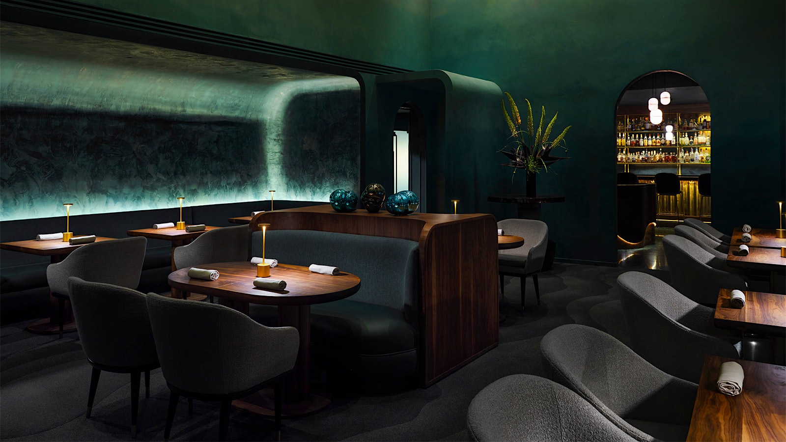 The dining room at Providence with deep blue and gray hues, wood tables and a display wine cellar in the background